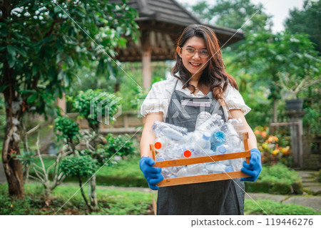asian woman wearing apron holding plastic bottle in wooden storage asian woman wearing apron holding plastic bottle in wooden storage 119446276