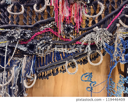 A ropes piece of art is displayed on a wooden wall 119446409