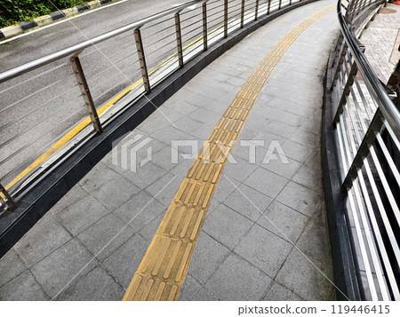 Curved path with guardrail and yellow line for blind people along the road Curved path with guardrail and yellow line for blind people along the road 119446415