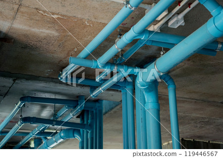 A bright blue pipes attached to a solid concrete wall 119446567