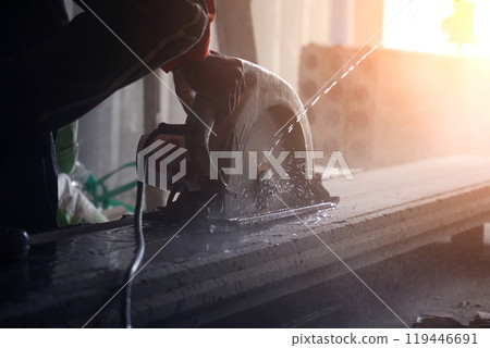 A builder using a circular saw to cut a large concrete piece A builder using a circular saw to cut a large concrete piece 119446691