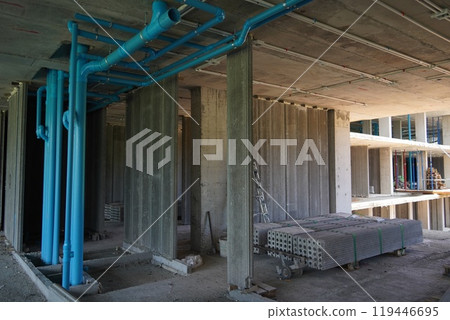 A large building currently under construction that has many blue pipes 119446695
