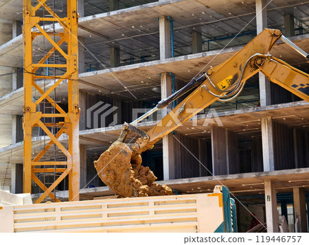 Excavator loads ground into a dump truck at a construction site 119446757