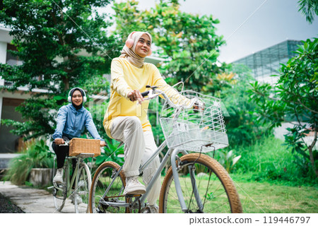 young veiled woman with headphones on a bicycle with friends cycling 119446797