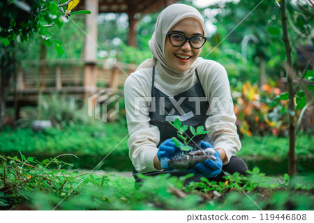 hijab woman happy to planting seedling into plastic bottle 119446808
