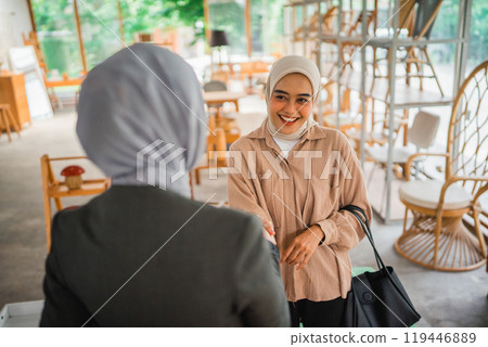 smiling veiled female customer shakes hands with the shop owner smiling veiled female customer shakes hands with the shop owner 119446889
