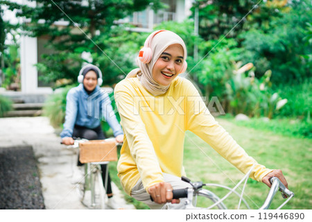Two friends happily enjoy a leisurely bike ride in a scenic park with nature 119446890
