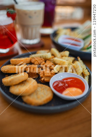 nuggets, sausages and fries served with ketchup on a table 119447250