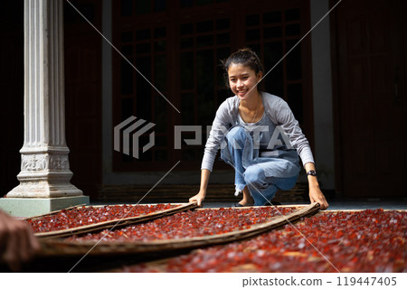 A Young Woman Skillfully Arranging Beautiful Traditional Rugs in a Cultural Setting 119447405