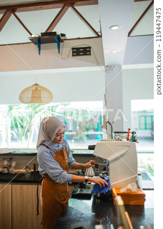 veiled woman waitress cleaning espresso coffee maker before customers arrive 119447475