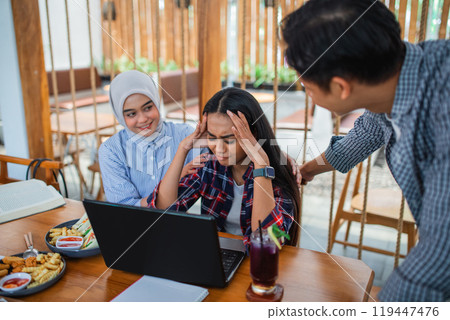 Group of young Asian students face problems when using a laptop computer together 119447476