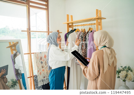 Muslim fashion designer in a headscarf shows a new dress with a customer 119447495