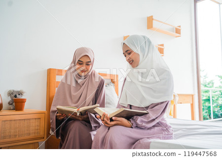 Two women are reading together in a cozy room that feels warm and inviting 119447568