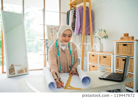Asian woman Muslim fashion designer is sketching with a ruler 119447672