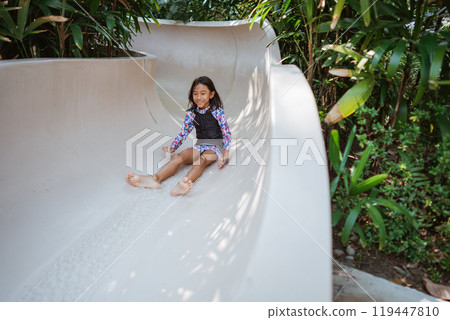 Exciting Slide Adventure A Child Joyfully Playing Outdoors in a Tropical Setting 119447810
