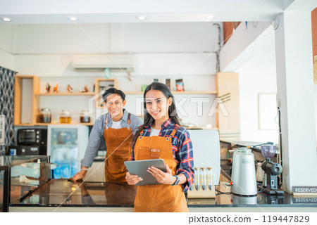 beautiful woman shop owner wearing apron smiling holding a tablet 119447829