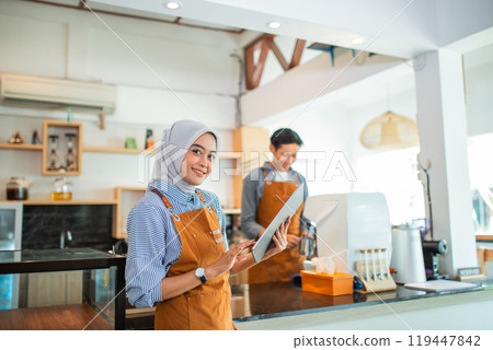 veiled female waitress using a tablet against the background of male waiters 119447842