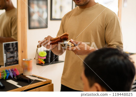 A man is currently having his hair cut by a barber in a barber shop 119448025