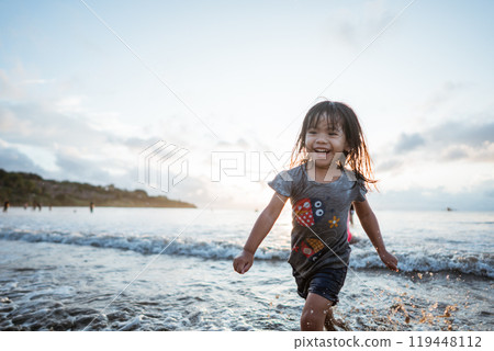 A Joyful Child is Happily Playing in the Ocean During a Beautiful Sunset A Joyful Child is Happily Playing in the Ocean During a Beautiful Sunset 119448112