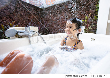 A girl is joyfully bathing in a cozy, warm bathtub 119448148