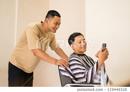 A man is skillfully cutting his hair while simultaneously taking a selfie 119448326