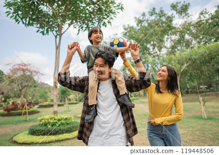 little boy is carried on the shoulder by his father while playing ball 119448506