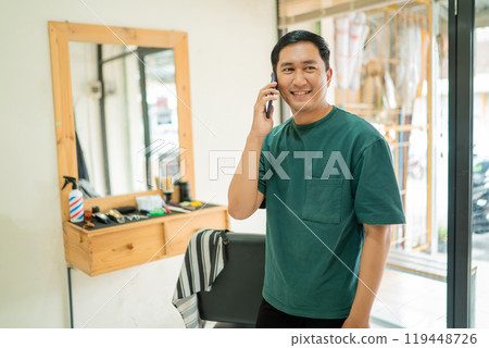 A man is on a cell phone in a barber shop discussing topics 119448726