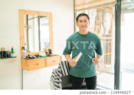 A man in a barber shop is holding scissors and a razor A man in a barber shop is holding scissors and a razor 119448827