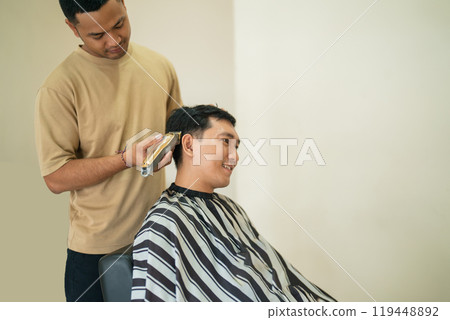 A man is currently getting his hair cut by a barber in a salon 119448892