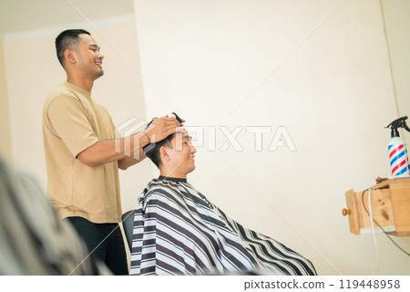 A man is getting his hair stylishly cut by a barber 119448958