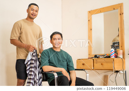 A man sits comfortably in a chair while his barber cuts hair 119449006