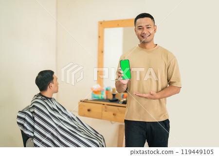 A man gets a haircut from a barber while using a cell phone A man gets a haircut from a barber while using a cell phone 119449105