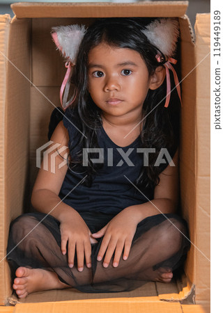 A Young Girl Enthusiastically Posing in a Cardboard Box Dressed in a Cat Ears Costume A Young Girl Enthusiastically Posing in a Cardboard Box Dressed in a Cat Ears Costume 119449189
