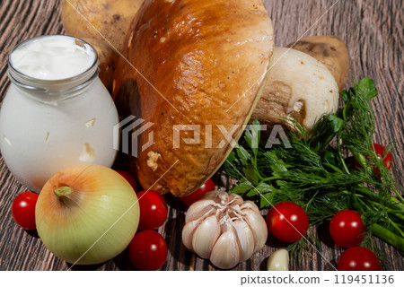 Roast mushroom Boletus edulis. Ingredients for cooking roast: large mushroom Boletus edulis, potatoes, sour cream, onion, garlic, tomatoes 119451136