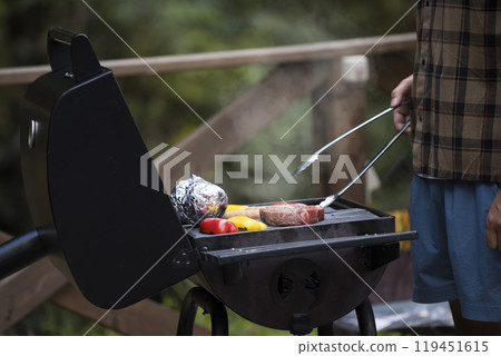 一名男子在豪華露營設施的烤肉爐上手工烤肉食材 119451615