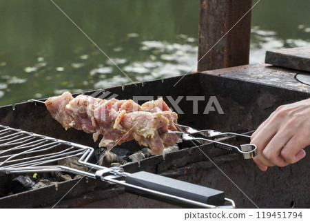 closeup of some meat skewers being grilled in a barbecue closeup of some meat skewers being grilled in a barbecue 119451794