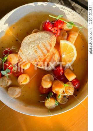 Fried Portuguese scallops in white wine sauce with lemon, tomatoes and toast. Seafood. Fried Portuguese scallops in white wine sauce with lemon, tomatoes and toast. Seafood. 119451824