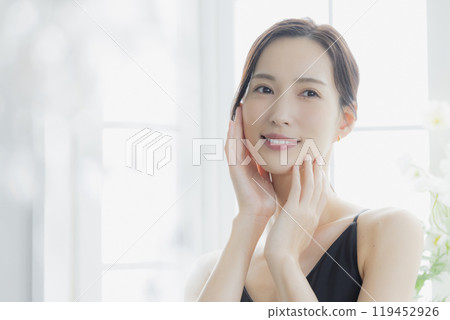 A woman in a black camisole dress standing by the window A woman in a black camisole dress standing by the window 119452926