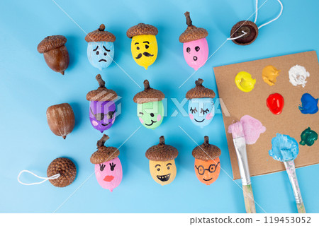 Painted acorns with emoji faces on blue backdrop, flat lay style. Vibrant autumn craft for greeting cards, seasonal banners, DIY art projects, and playful designs., 119453052