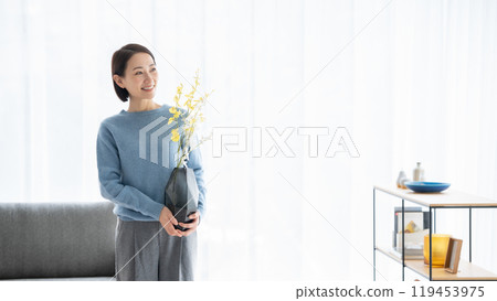 Woman arranging flowers in living room Woman arranging flowers in living room 119453975