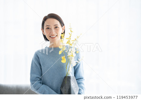 Woman arranging flowers in living room 119453977