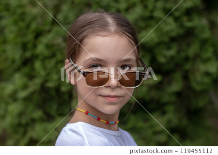Fashionable little girl in sunglasses looking at the camera Fashionable little girl in sunglasses looking at the camera 119455112