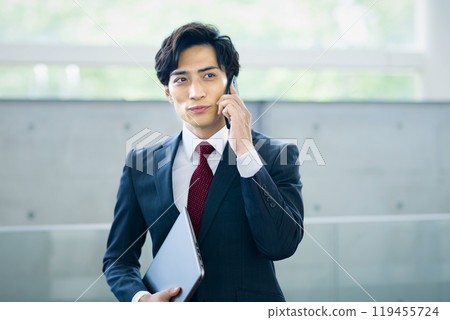 A businessman in a suit calling on a smartphone in the office 119455724