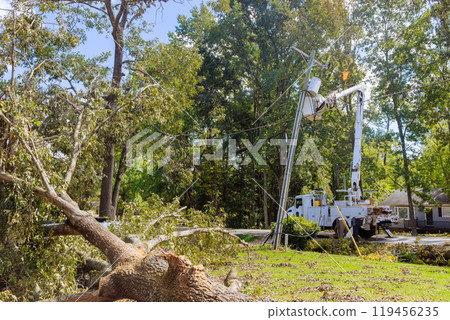 Using utility tower truck, emergency service linemen are diligently repairing power electrical lines damaged by hurricanes Using utility tower truck, emergency service linemen are diligently repairing power electrical lines damaged by hurricanes 119456235