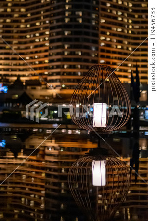 A floor lantern, with reflection on the pond. with bokeh background of the night city view A floor lantern, with reflection on the pond. with bokeh background of the night city view 119456733