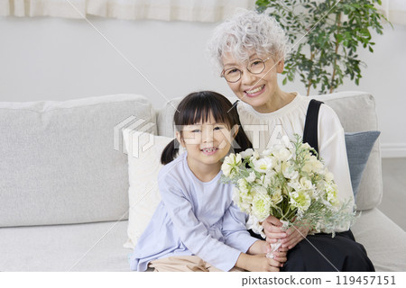 Grandmother and grandchild holding bouquet, living room, looking at camera 119457151
