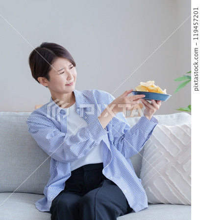 A woman wondering whether to eat potato chips (potato chips, diet, gain weight, unhealthy) 119457201