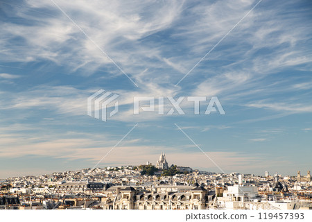 Beautiful view of Montmartre hill and Sacre Coeur Basilica against a blue sky with clouds 119457393