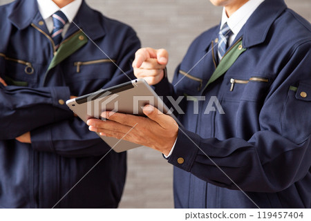 A middle-aged male businessman in work clothes working on a tablet A middle-aged male businessman in work clothes working on a tablet 119457404