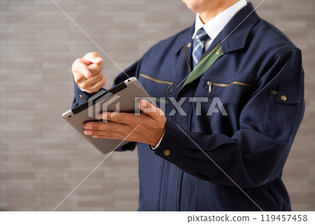 A middle-aged male businessman in work clothes working on a tablet 119457458